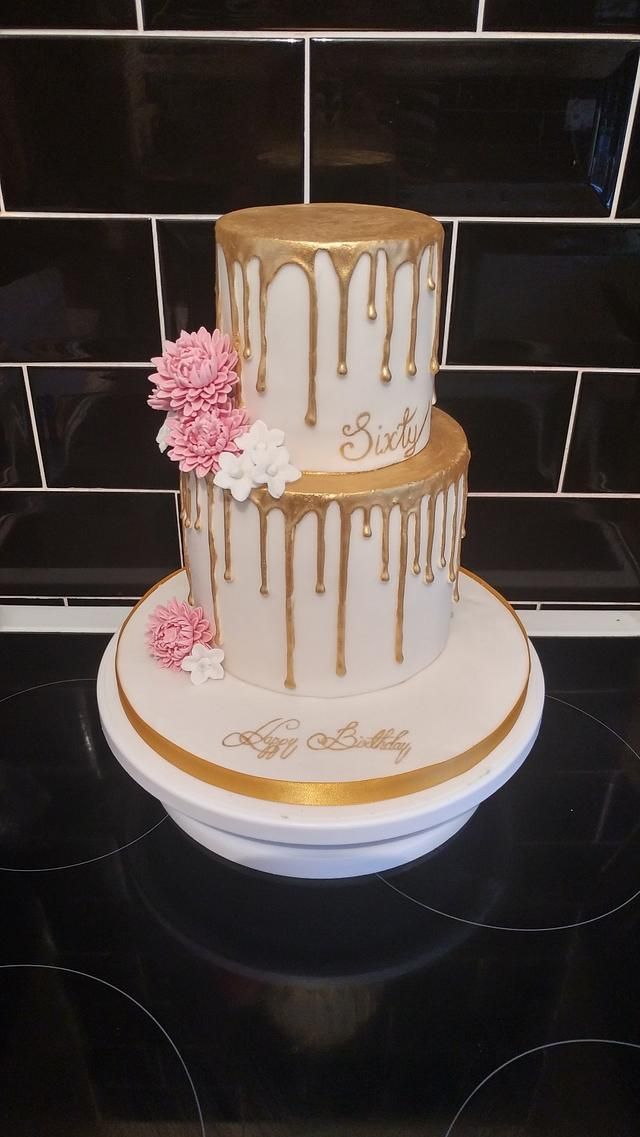 a three tiered cake with white and gold icing on top, decorated with pink flowers