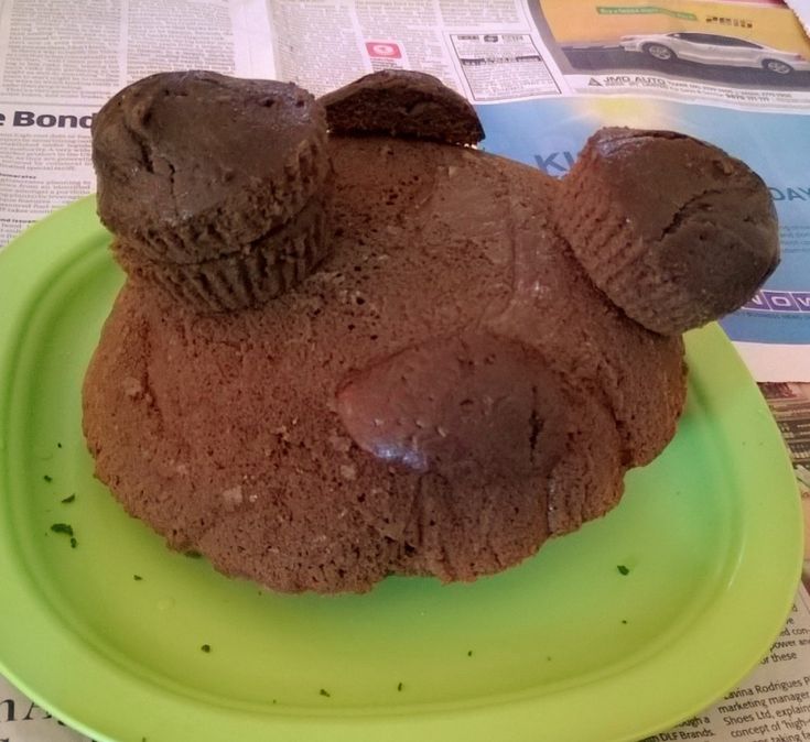 a close up of a chocolate cupcake on a plate with newspaper in the background