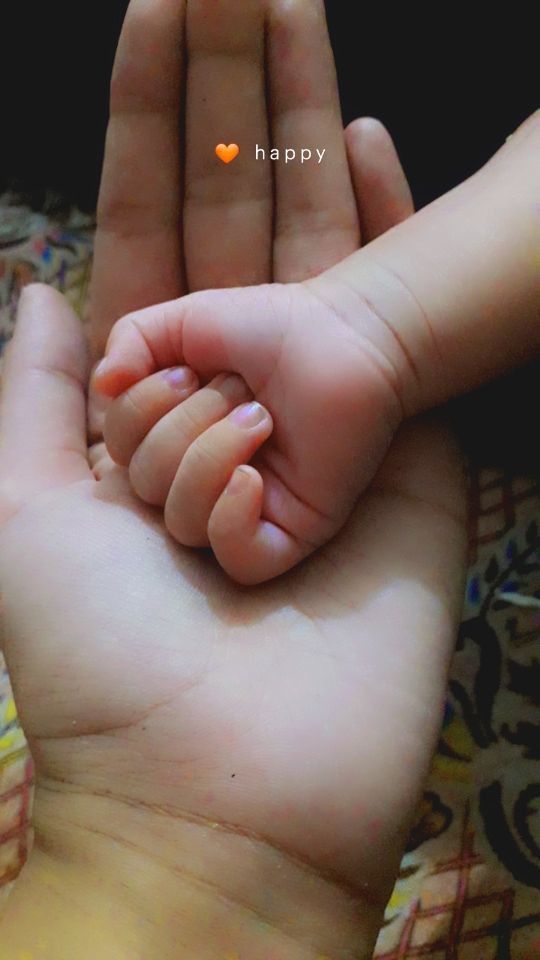 a person holding a baby's hand with an orange heart in the middle of it