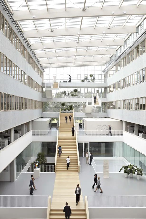 people are walking up and down the stairs in an open area with many windows on both sides