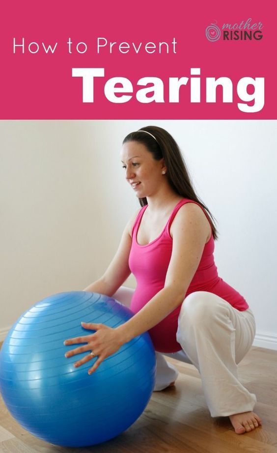 a woman sitting on an exercise ball with her hands on the ground and smiling at the camera