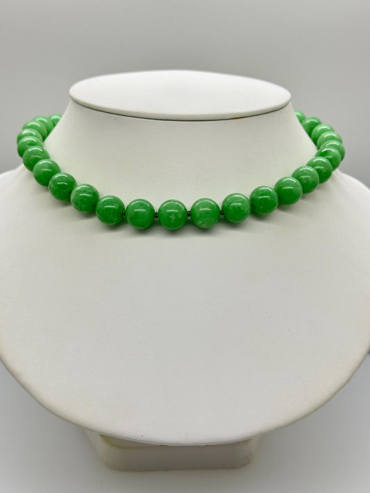 Green Jade Jadeite Bead Necklace.  This hand knotted necklace features 32 Green Jade Jadeite Beads Round Polished Grade AAA 11.9 to 12.4mm.  I hand knotted these with green silk thread and finished them with a 925 Silver Fold Over Magnetic Clasp.  The necklace measures 18 inches in length.  Please keep in mind that large beads take up space on the neck and they will fit tighter than an 18 inch chain.  The Beads are Genuine and Natural in color, no treatments.  The necklace pictured is the one you will receive.   It will arrive in a nice presentation box with a Certificate of Authenticity.   Please visit our Shop for more Pearls and Gemstone Jewelry. Classic Green Jewelry With 8mm Beads, Classic Jade Necklaces With Round Beads, Classic Green Beaded Necklaces With Round Beads, Classic Jade Necklace With Round Beads, Formal Green Single Strand Beaded Necklace, Single Strand Jade Beaded Necklace With Round Beads, Green Single Strand Necklace With Round Beads, Classic Green Gemstone Beads Necklace, Elegant Single Strand Green Beads