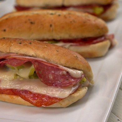 two sub sandwiches with meat and cheese on them