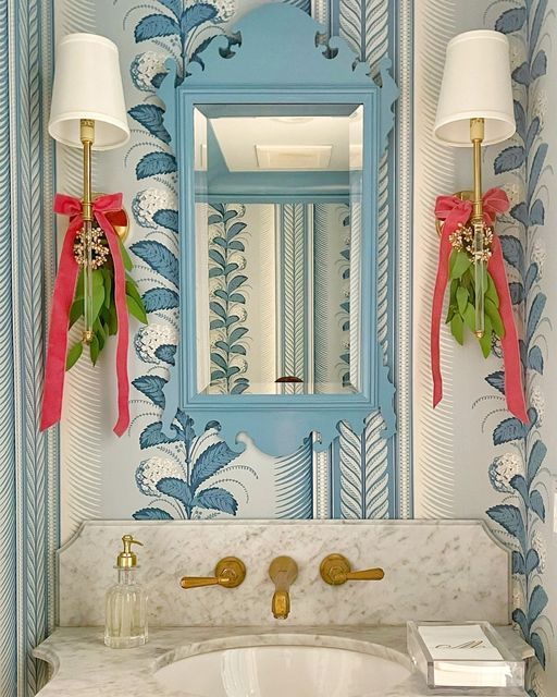 a bathroom decorated in blue and white with pink bows on the sink, mirror and lights