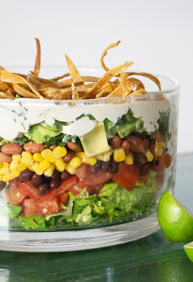 a salad in a glass bowl with corn and avocado