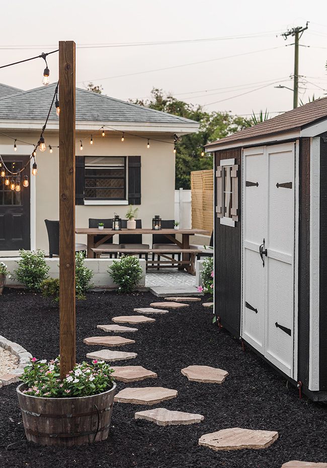 a small backyard with stepping stones leading up to the shed