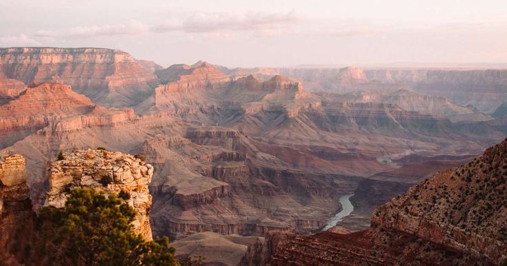 the sun is setting at the edge of the grand canyon, with water running through it