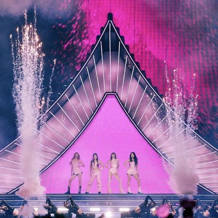 the girls are performing on stage with fireworks in the background