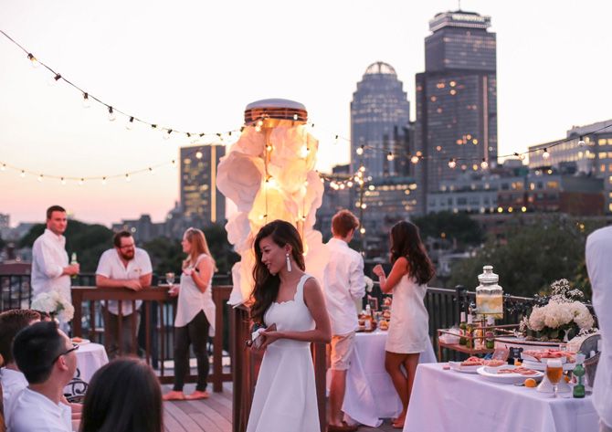 a woman in a white dress standing next to a table filled with food and drinks