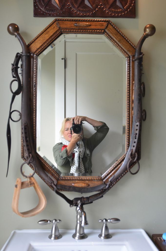 a woman taking a selfie in front of a bathroom mirror with scissors on the wall