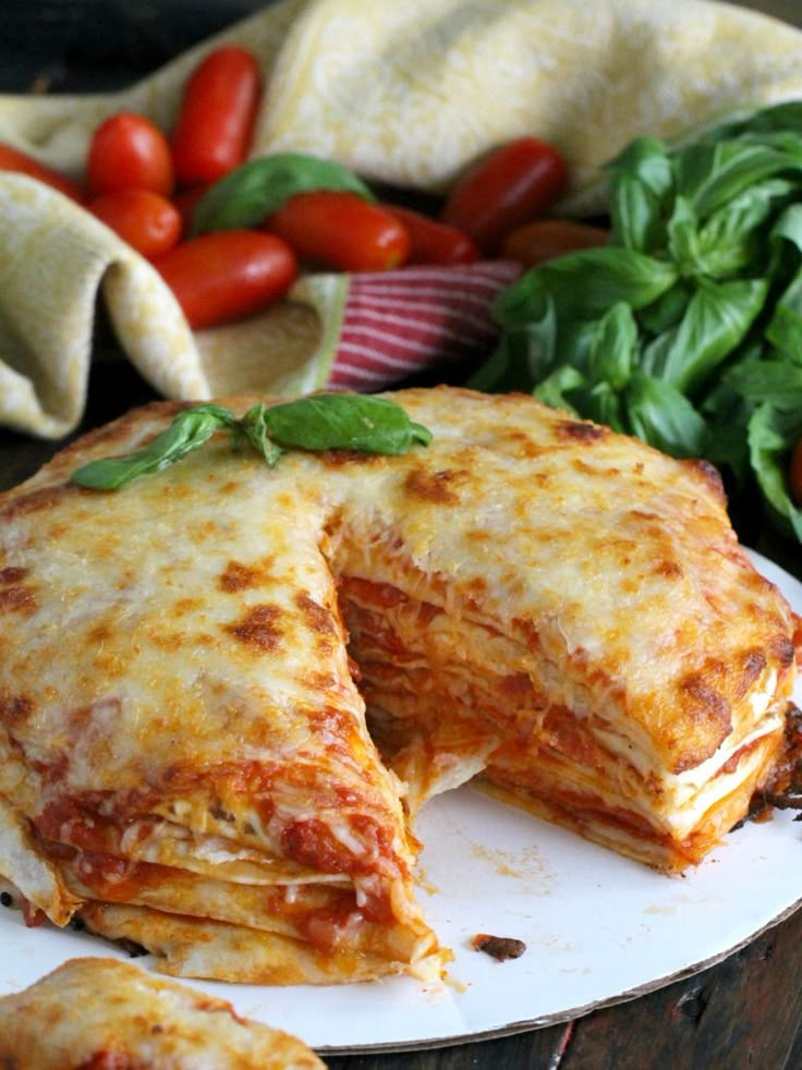 a plate that has some food on top of it with tomatoes and spinach in the background