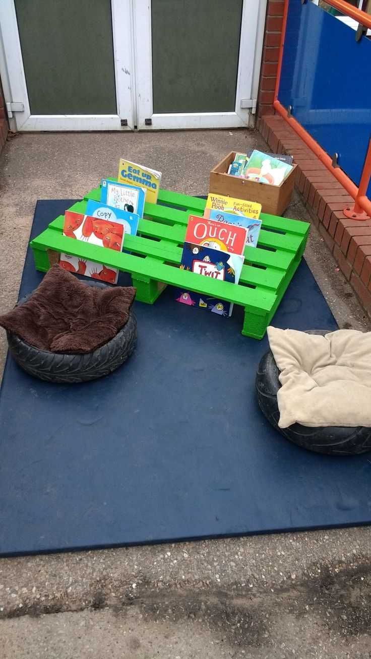 some books are sitting on top of a green pallet and there is a dog bed next to it