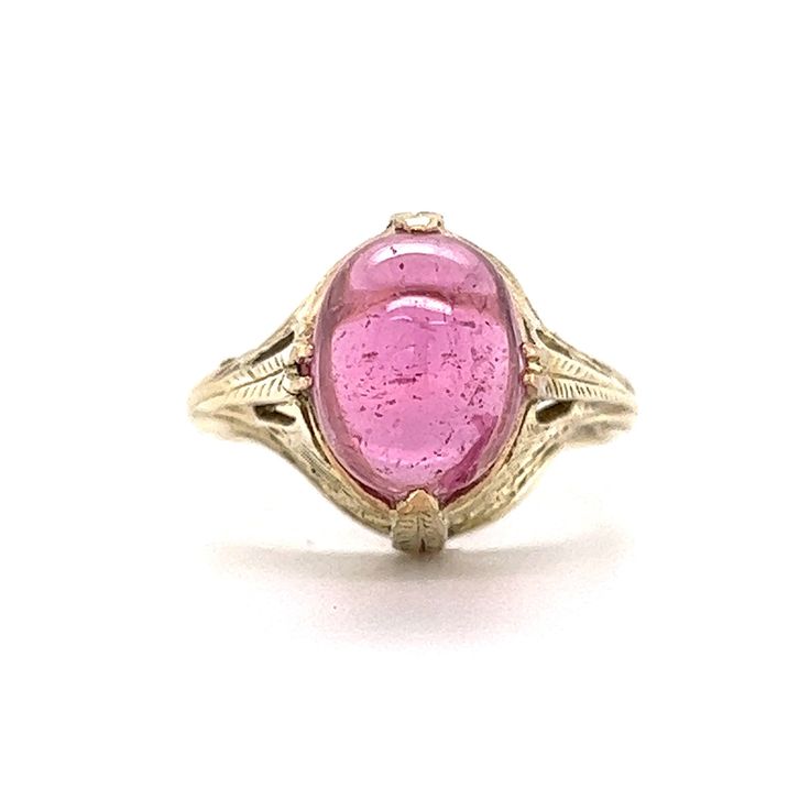 Art Deco Cabochon Cut Pink Tourmaline Ring in 14k Yellow Gold This one of a kind Art Deco ring features a light pink tourmaline in 14 karat yellow gold. The tourmaline reflects a romantic, taffy pink hue. Cabochon cut and smoothly polished. The antique shoulders of the band feature geometric engravings. Decorative and fashionable. Finished in 14 karat yellow gold. This statement cocktail ring is a treasure from the Art Deco era. PRIMARY STONE Stone: Pink Tourmaline Measurements: 10.48 mm x 8.03 Pink Round Cabochon Ruby Ring, Pink Cabochon Ruby Ring, Formal Pink Rings With Polished Finish, Pink Oval Tourmaline Jewelry, Pink 14k Gold Jewelry With Polished Finish, Yellow Gold Tourmaline Cabochon Ring, Classic Pink Cabochon Jewelry, Pink Tourmaline Sapphire Ring, Pink Oval 14k Stamped Jewelry