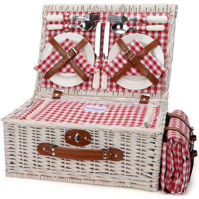 a picnic basket with two plates and utensils in it, sitting on top of a table