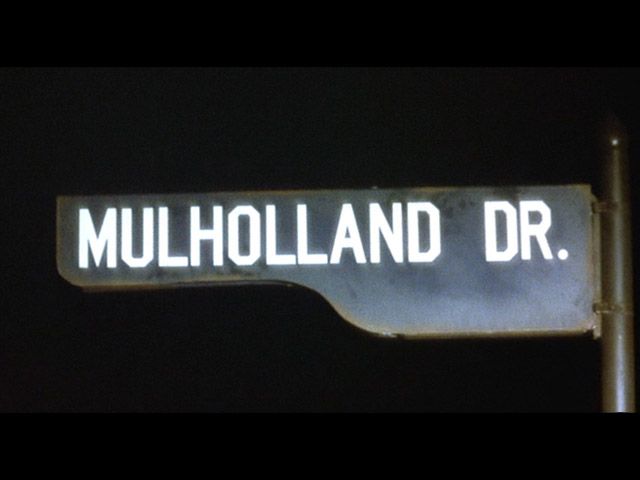 a street sign with the word mulholand dr written on it at night time