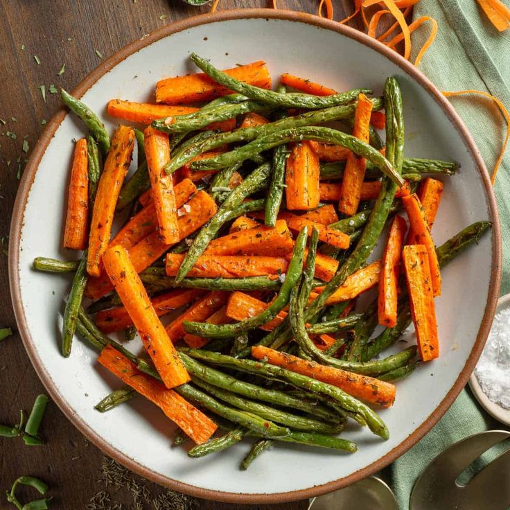 a white bowl filled with green beans and carrots