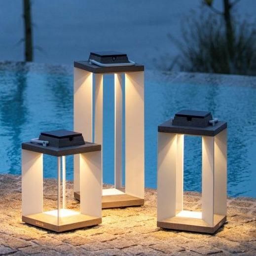 three white lanterns sitting next to a swimming pool