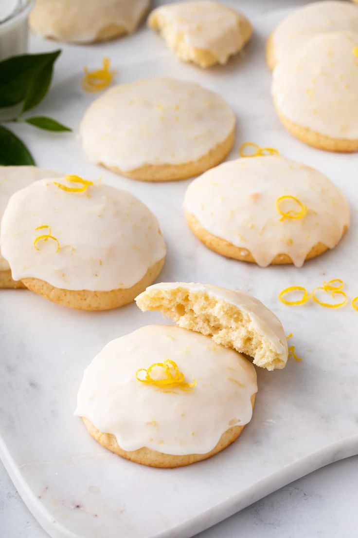 iced lemon cookies with icing and orange zest on a white marble platter