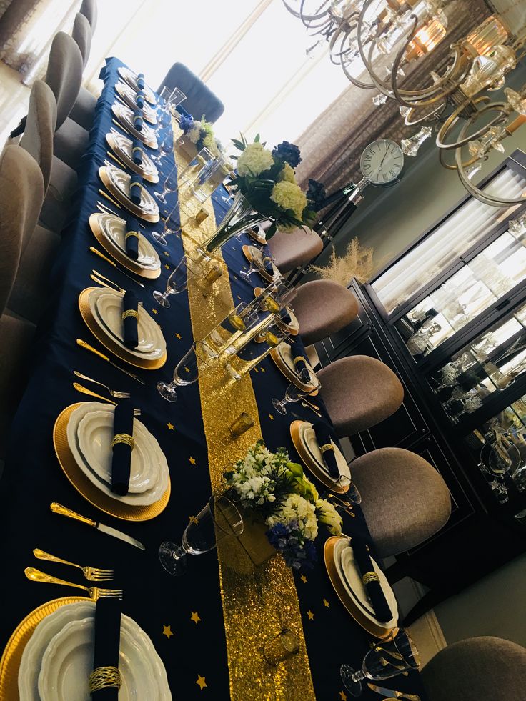 the table is set with gold and black plates, silverware, and napkins