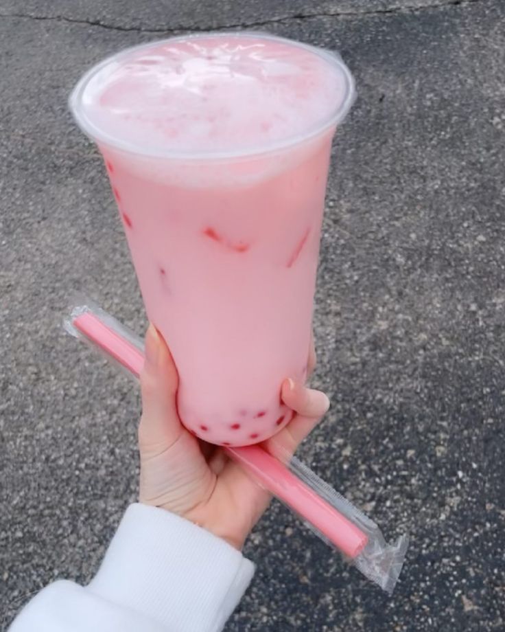 a person holding a pink drink in their hand