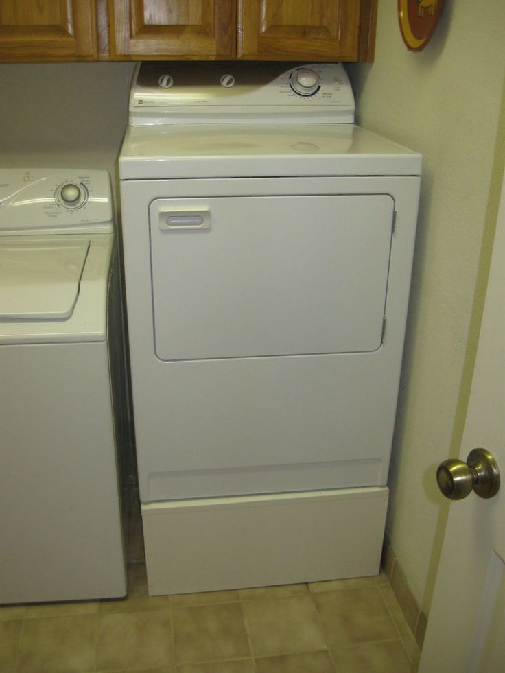 a washer and dryer in a small room with wood cabinets on the wall