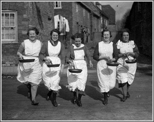 four women in aprons are walking down the street