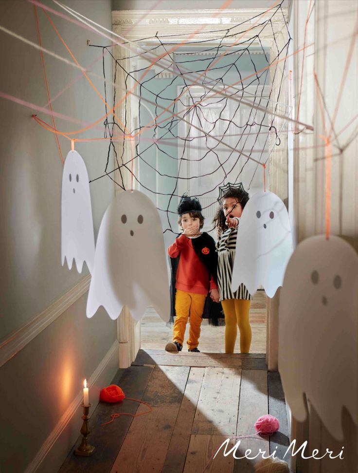 two children standing in front of halloween decorations