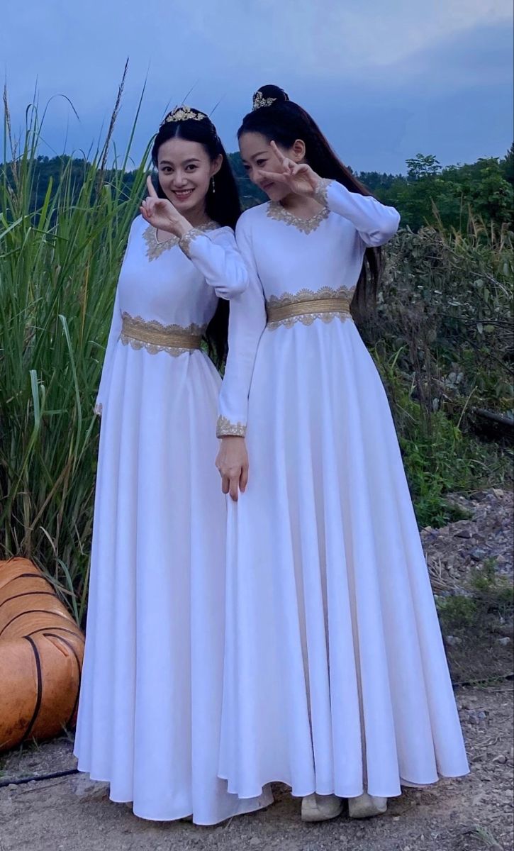 two women in white dresses standing next to each other