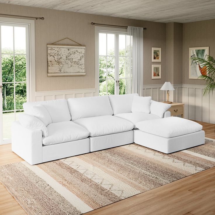 a large white couch sitting on top of a wooden floor next to a lamp and window