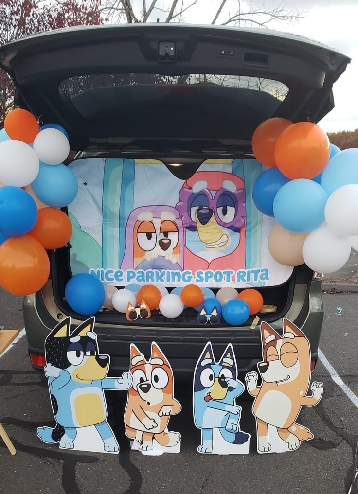 the back of a car with balloons and decorations on it's trunk, including an image of cartoon characters