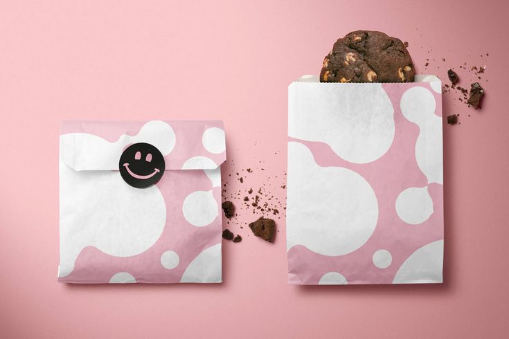 an envelope with a smiley face on it next to a cookie in the shape of a bag