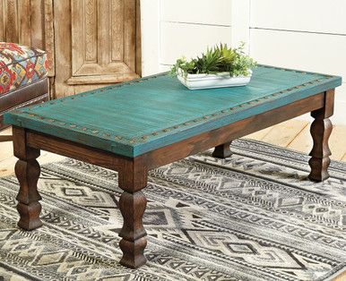 a wooden table with a plant on top of it in front of a chair and rug