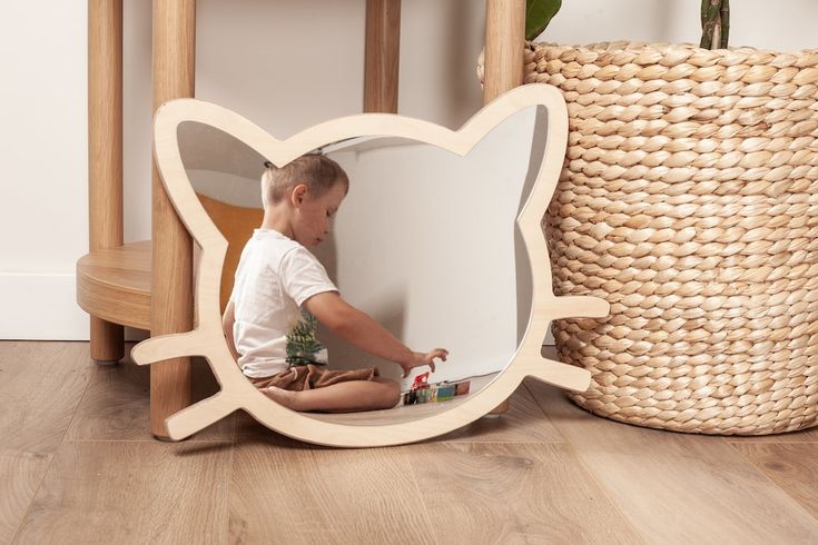 a young boy sitting on the floor in front of a mirror with a butterfly design