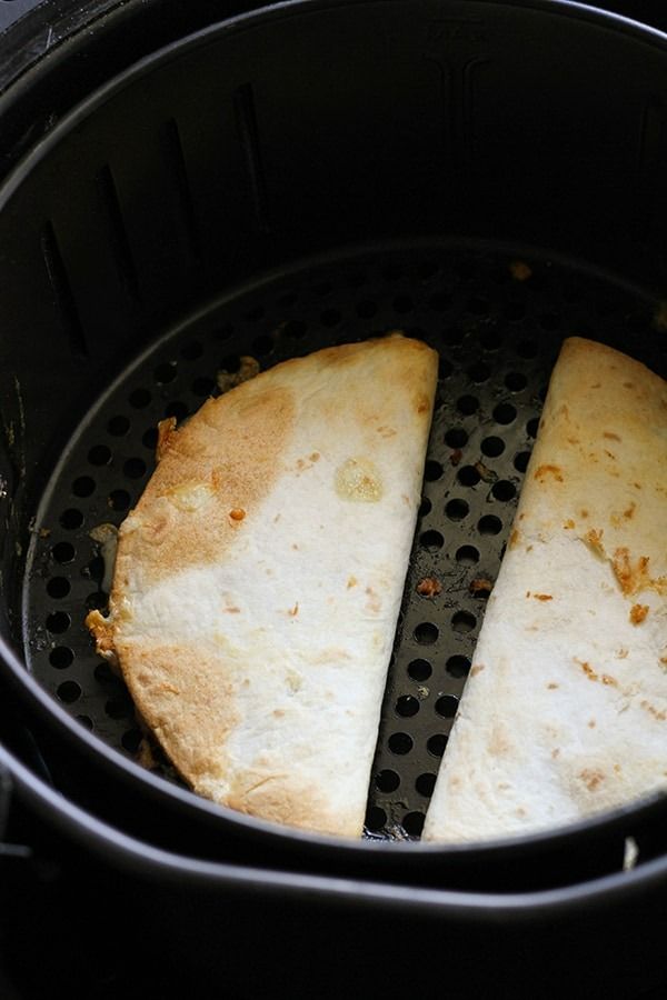 two pieces of pizza sitting in an air fryer