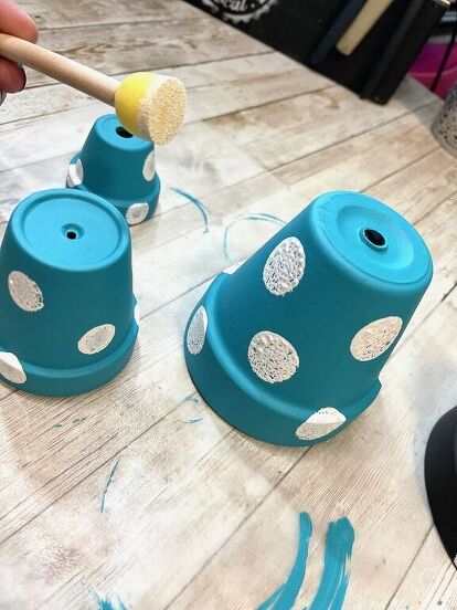 two blue vases sitting on top of a wooden table next to a person holding a brush