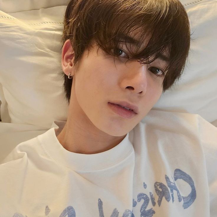 a young man laying in bed wearing a white shirt with the word crush on it