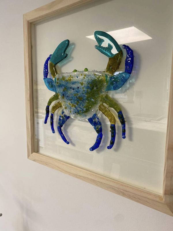 a blue and green crab in a frame on the wall next to a white wall