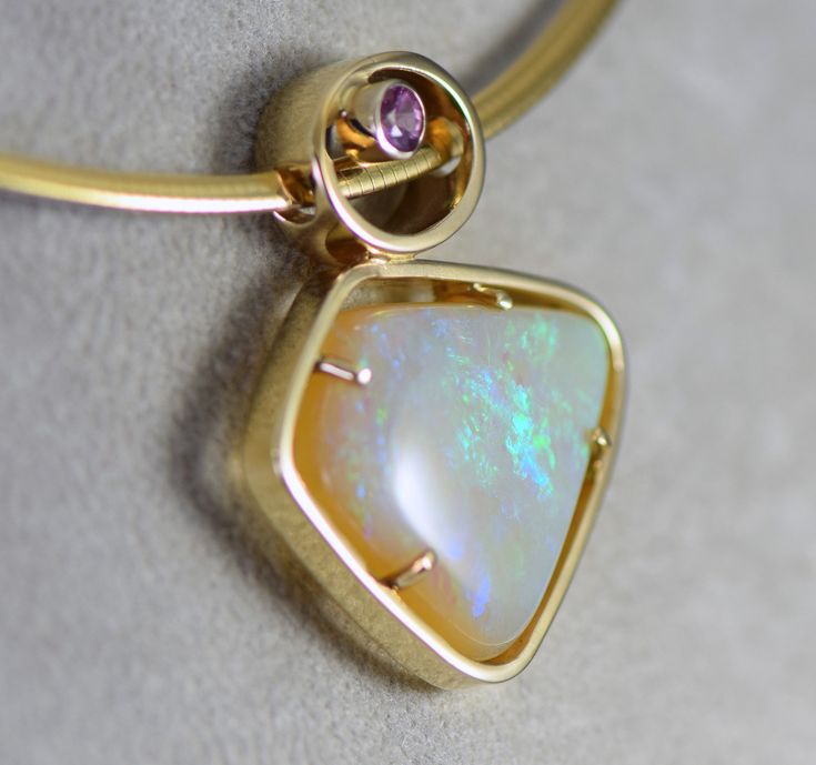 A lovely opal from Andamooka Australia is accented with a pink sapphire set in 14k yellow gold pendant. The Andamooka opal measures 19.5 x 24mm wide and weighs 13.94 carats The pink Sapphire from Thailand measures 3.5mm and weighs .25 carats The metal is 14k yellow gold and the pendant weighs 8.19 grams Jewelry from Stowe Gems arrives beautifully packaged in a gift box. If you have any questions about this piece or if we can help you with any of our other products please feel free to contact us. Multi-stone Ethiopian Opal Jewelry In Yellow Gold, Yellow Gold Ethiopian Opal Multi-stone Jewelry, Ethiopian Opal Multi-stone Yellow Gold Jewelry, Ethiopian Opal Multi-stone Jewelry In Yellow Gold, Elegant Pink Opal Yellow Gold Jewelry, Gold Oval Pink Opal Jewelry, Yellow Gold Pink Opal Jewelry For Gift, Oval Gold Jewelry With Pink Opal, Oval Pink Opal Gold Jewelry