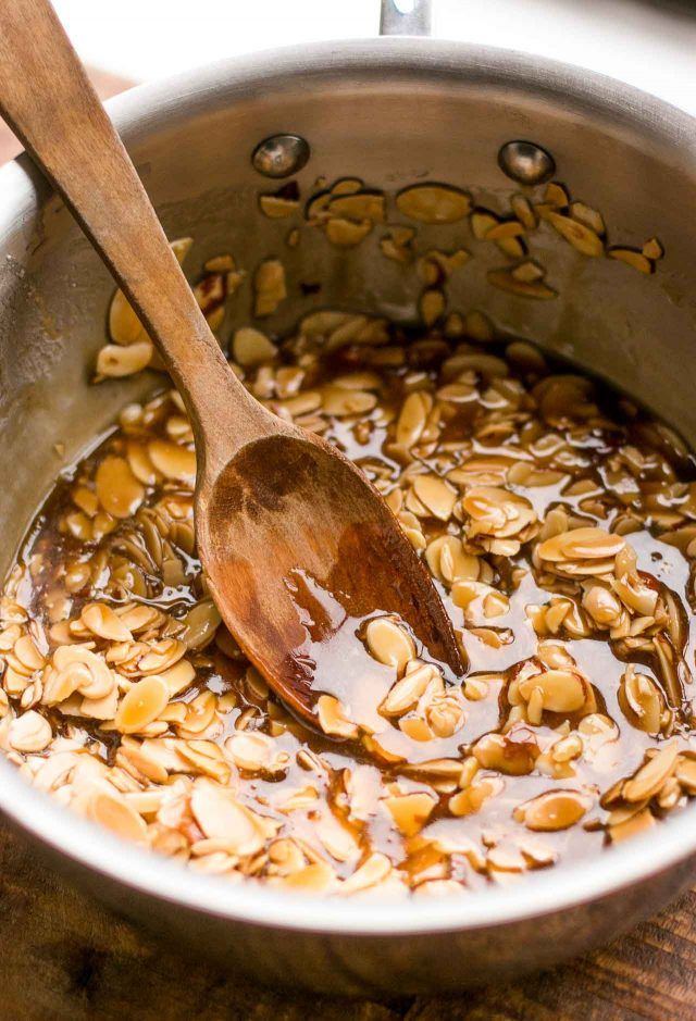 a wooden spoon in a pot filled with oatmeal and syrup on top of a table