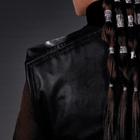 the back of a woman's black leather jacket with silver rings on her hair