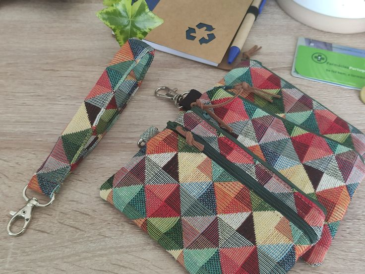 a multicolored purse sitting on top of a wooden table next to a book