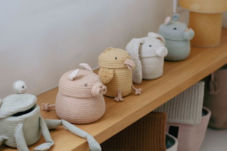 small crocheted toy animals lined up on a wooden shelf next to baskets and lamps