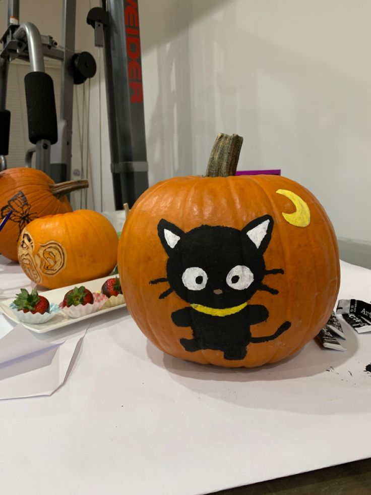 two pumpkins with faces painted on them sitting on a table