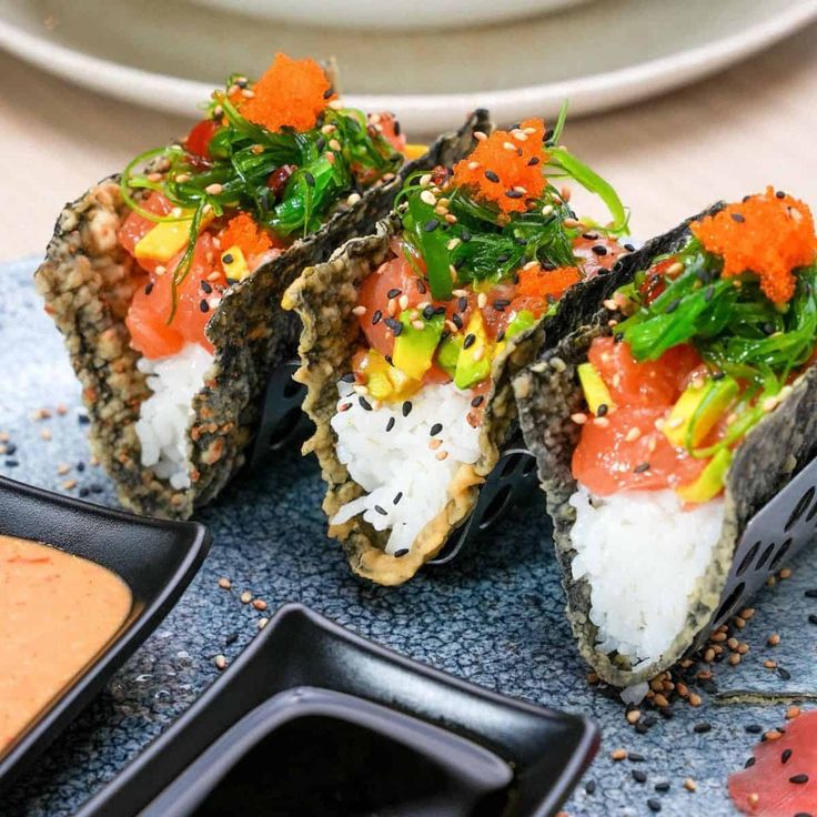 sushi is served on a plate with sauces and garnishes around it