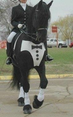 a woman riding on the back of a black and white horse in a parking lot