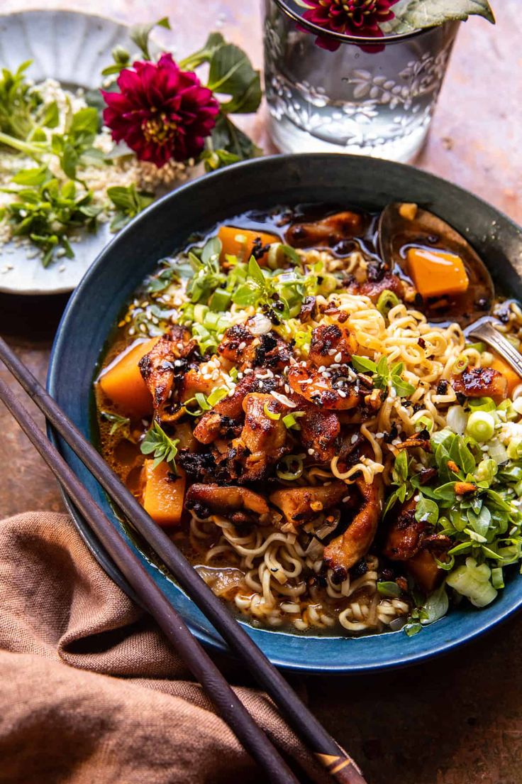 a bowl filled with noodles and vegetables next to chopsticks