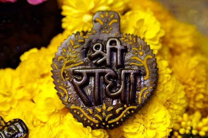 an ornate metal brooch with the word love and two letters on it, surrounded by yellow flowers