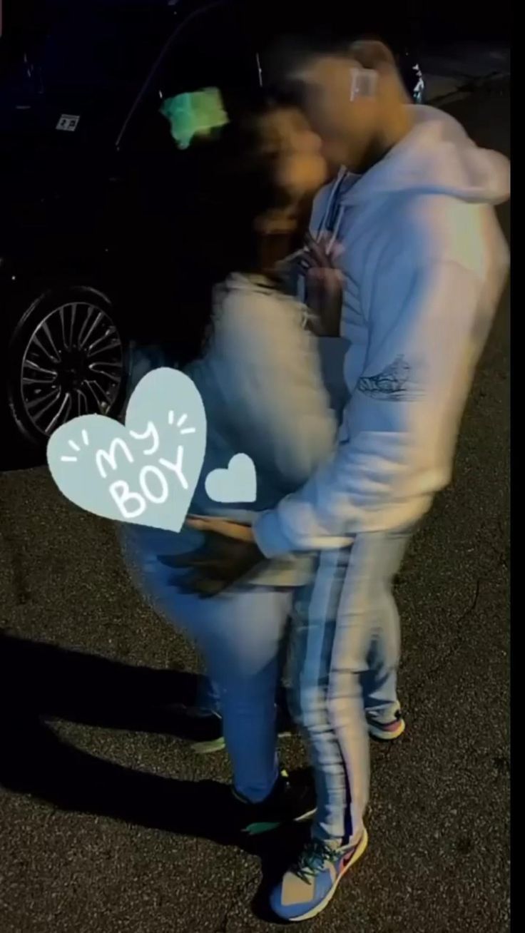 a man and woman standing next to each other in front of a car with the word i love you written on it