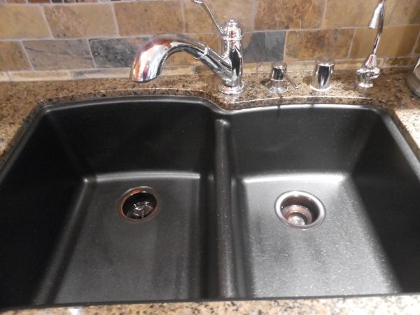 a kitchen sink with two faucets on the side and brown granite counter tops