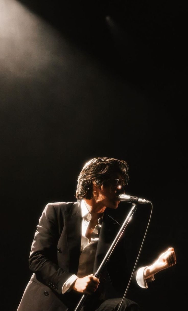 a man in a tuxedo singing into a microphone with his hands on the mic